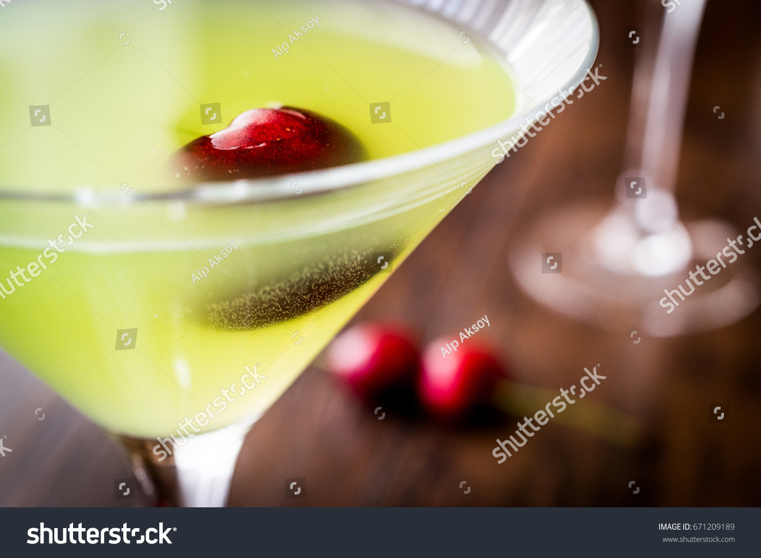 Appletini Cocktail with cherry on wooden surface.
 #671209189