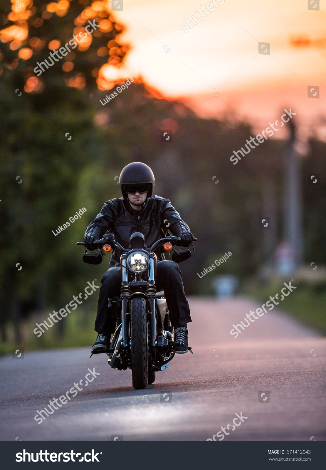 Man riding sportster motorcycle on countryside during sunset. #671412043