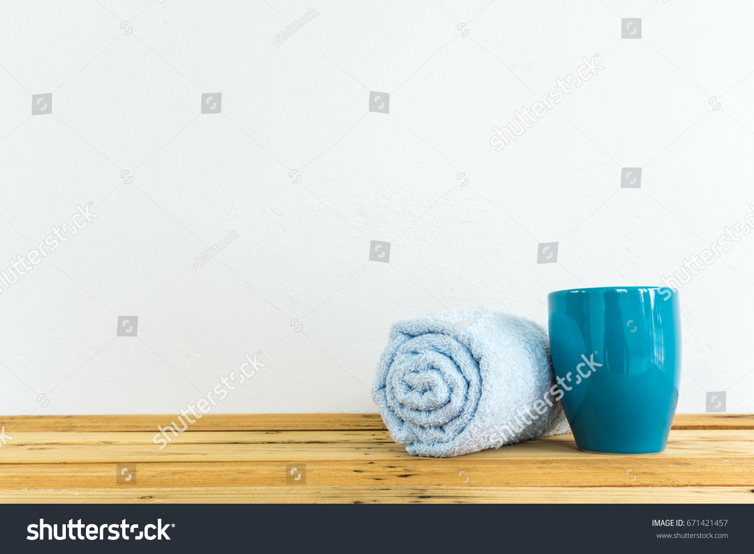 teal color coffee cup and cyan towel on wooden table with white cement wall background #671421457