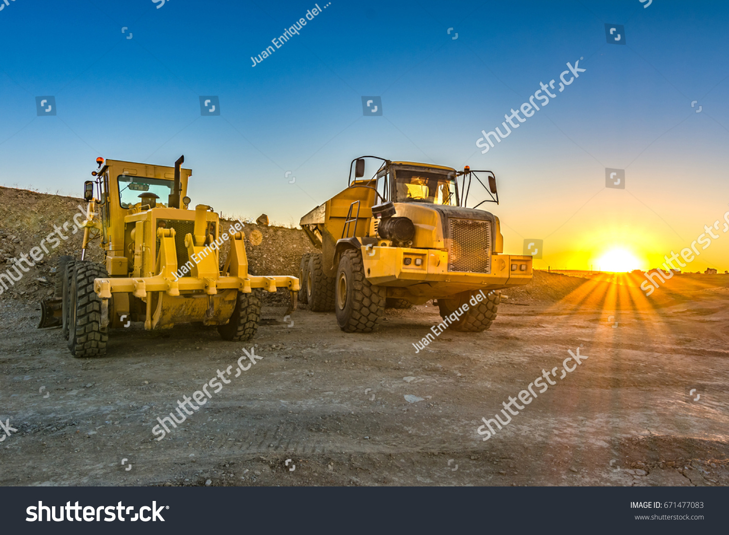 Excavator and trucks working on the excavation works of a road, moving rock and earth #671477083