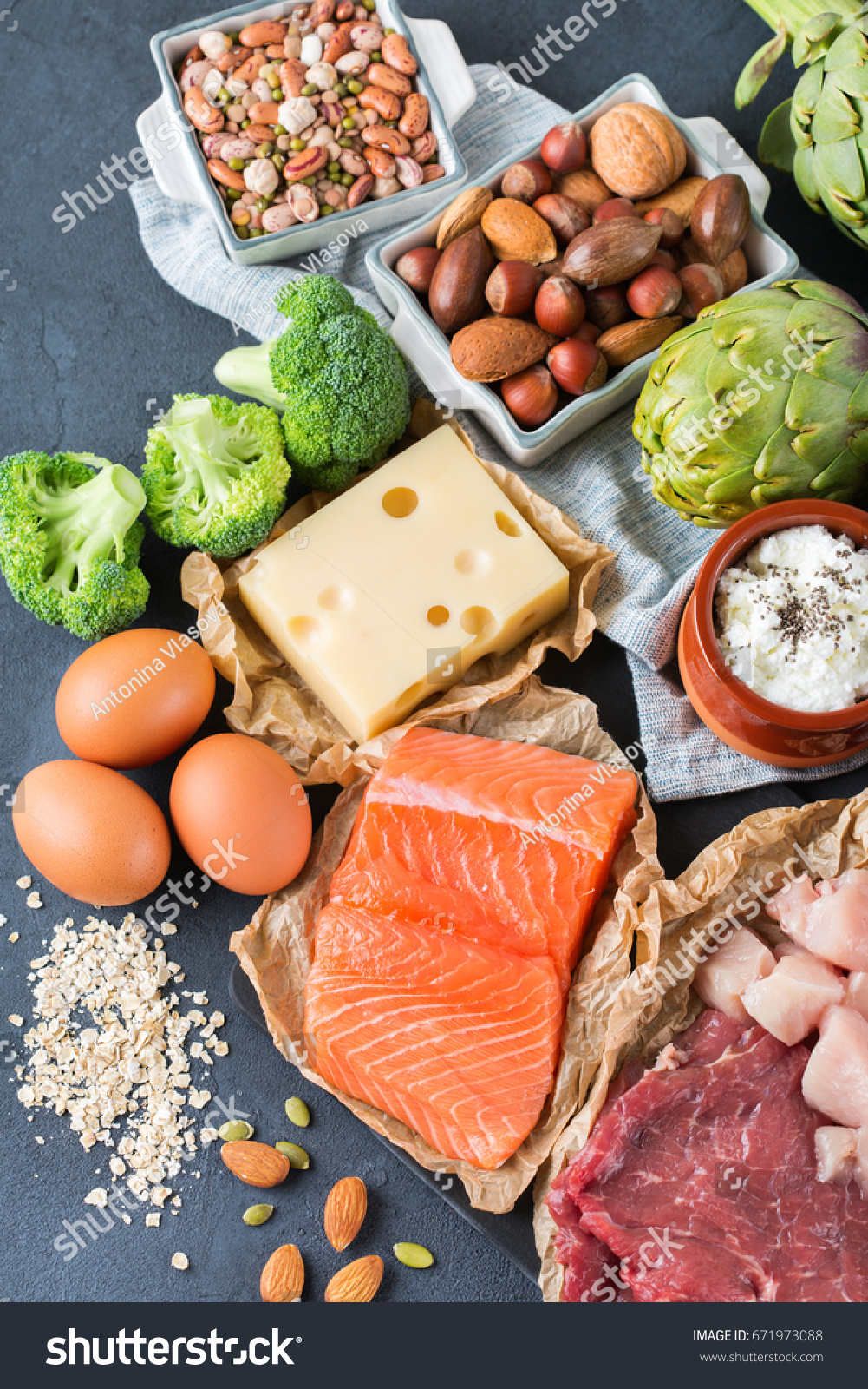 Assortment of healthy protein source and body building food. Meat beef salmon chicken breast eggs dairy products cheese yogurt beans artichokes broccoli nuts oat meal. Top view flat lay #671973088