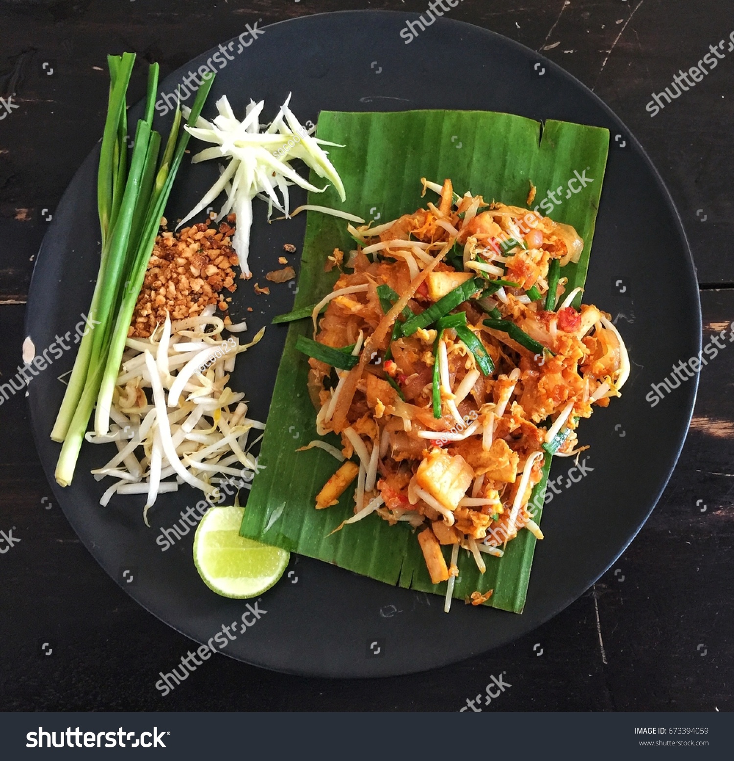 Fried noodle Thai style (pad thai) Delicious on a black plate on a wooden table that wants to be beautiful Causing hunger #673394059