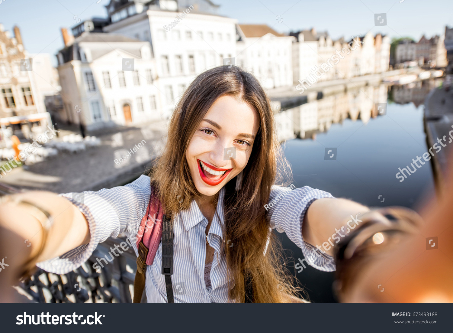 Young woman tourist making selfie photo standing on the bridge with beautiful view on Gent city in Belgium #673493188