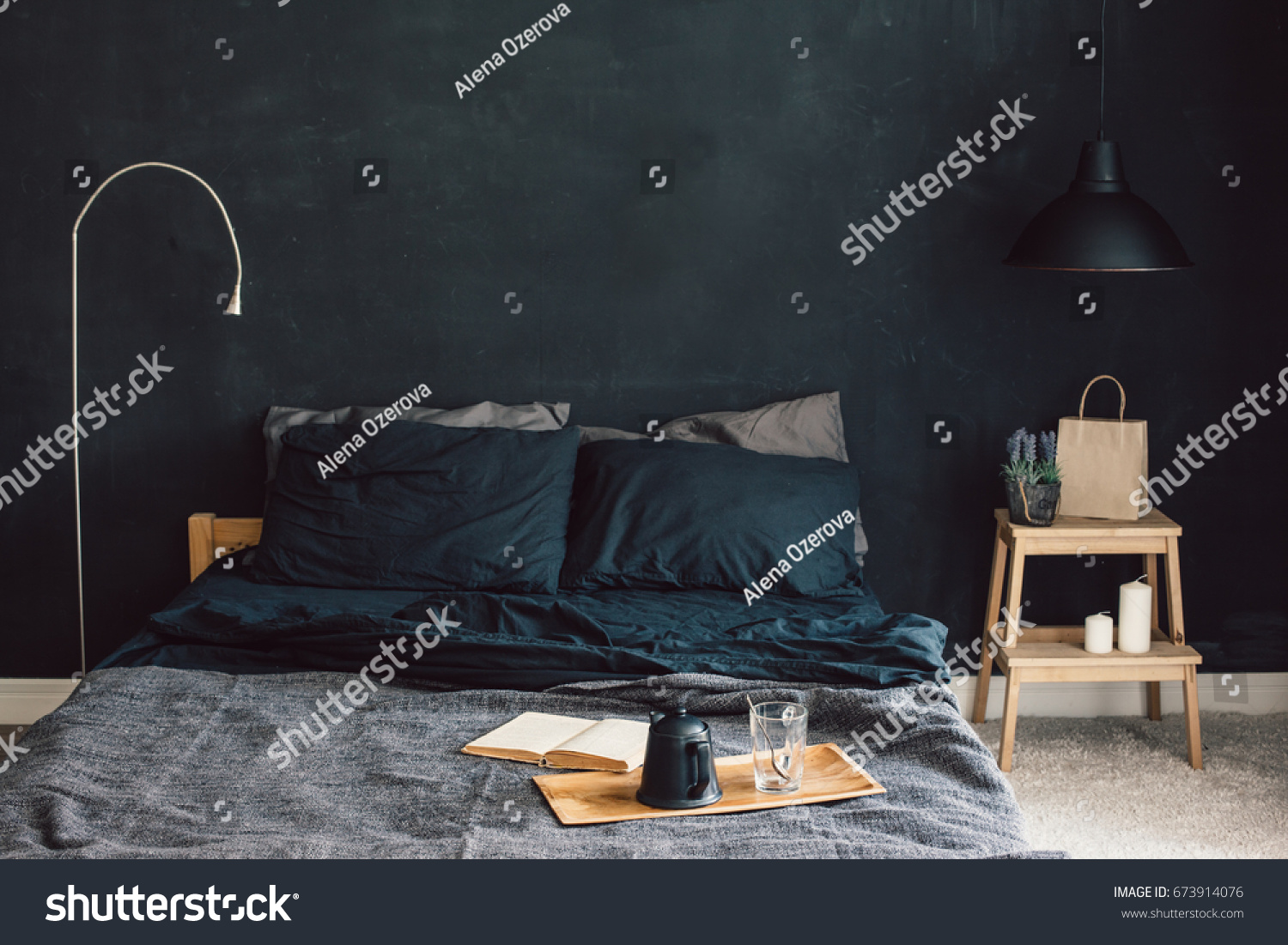 Black stylish loft bedroom. Unmade bed with breakfast and reading on tray. Lamp and interior decor over blank blackboard wall with copyspace. Cozy modern living space. #673914076