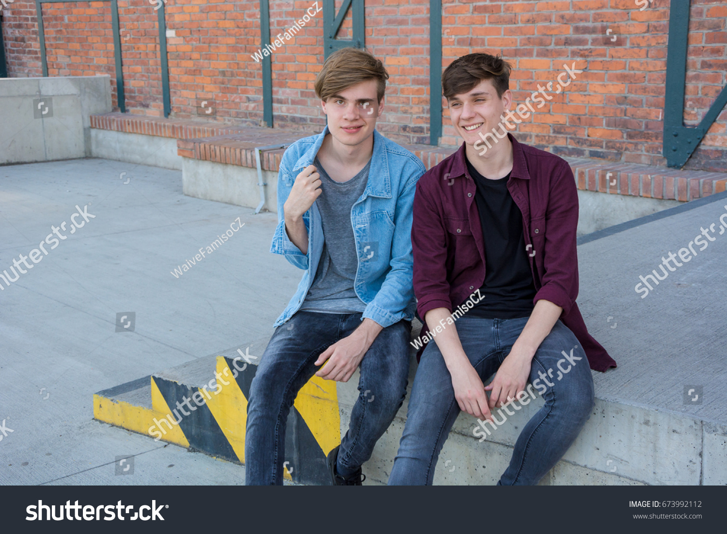 Two teenage boys brothers sitting on stairs at street talking and having fun, #673992112