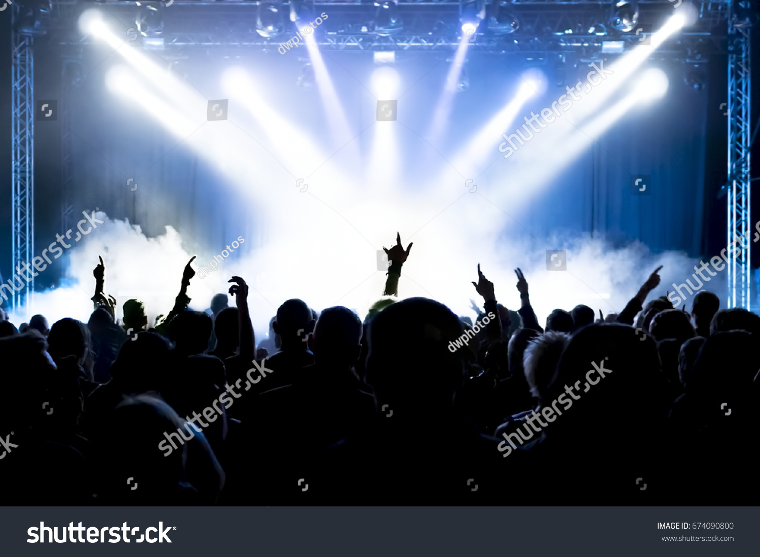 cheering crowd at rock concert in front of bright lights #674090800