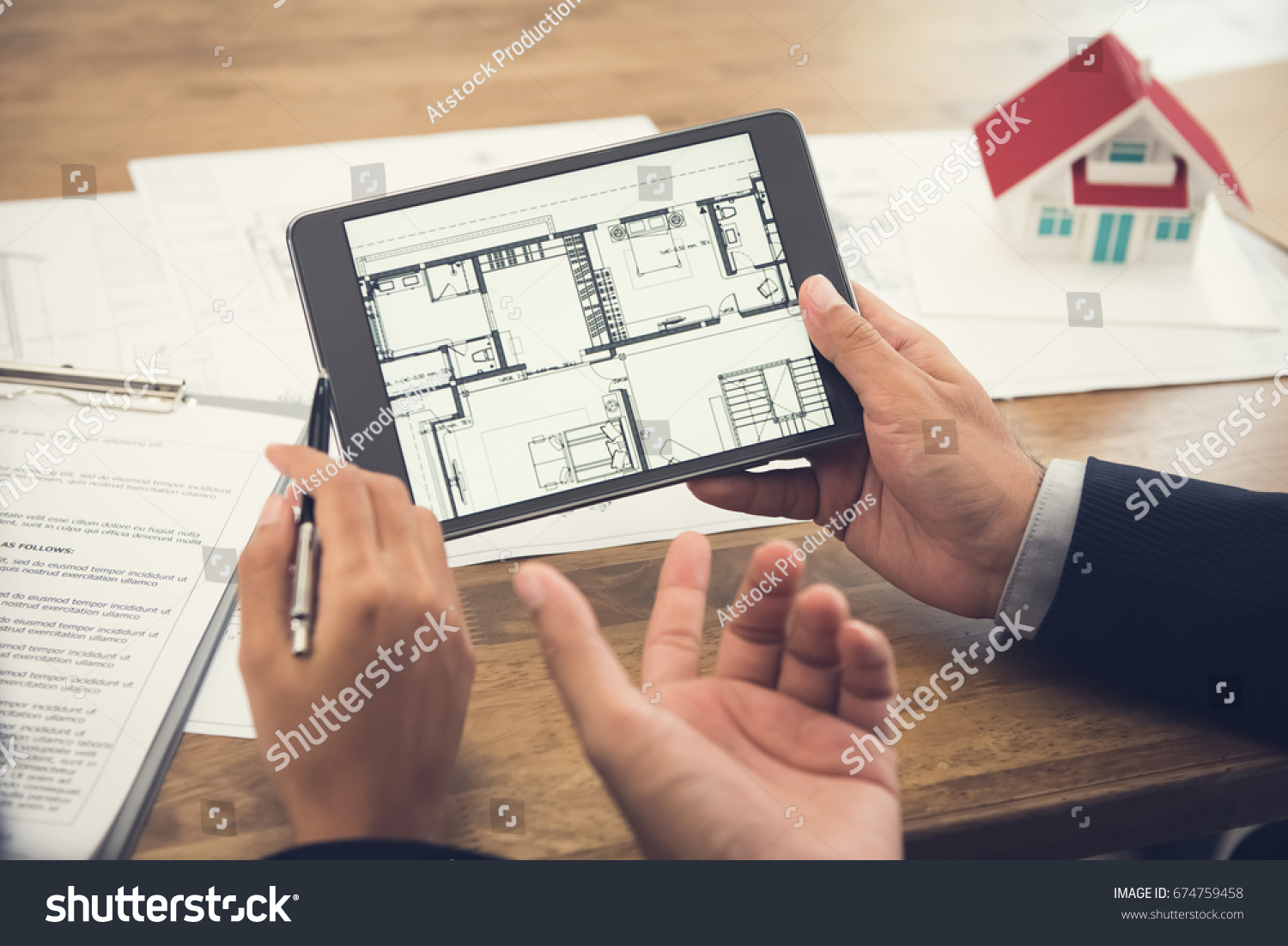 Real estate agent with client or architect team discussing house floor plan on tablet computer screen #674759458