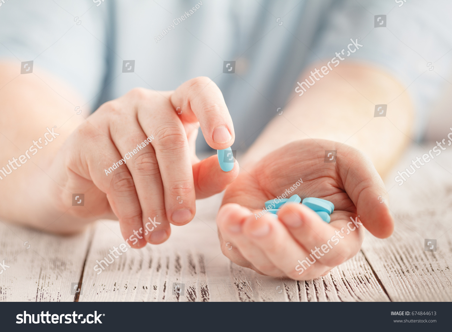 Male hand holding blue pills in palm #674844613