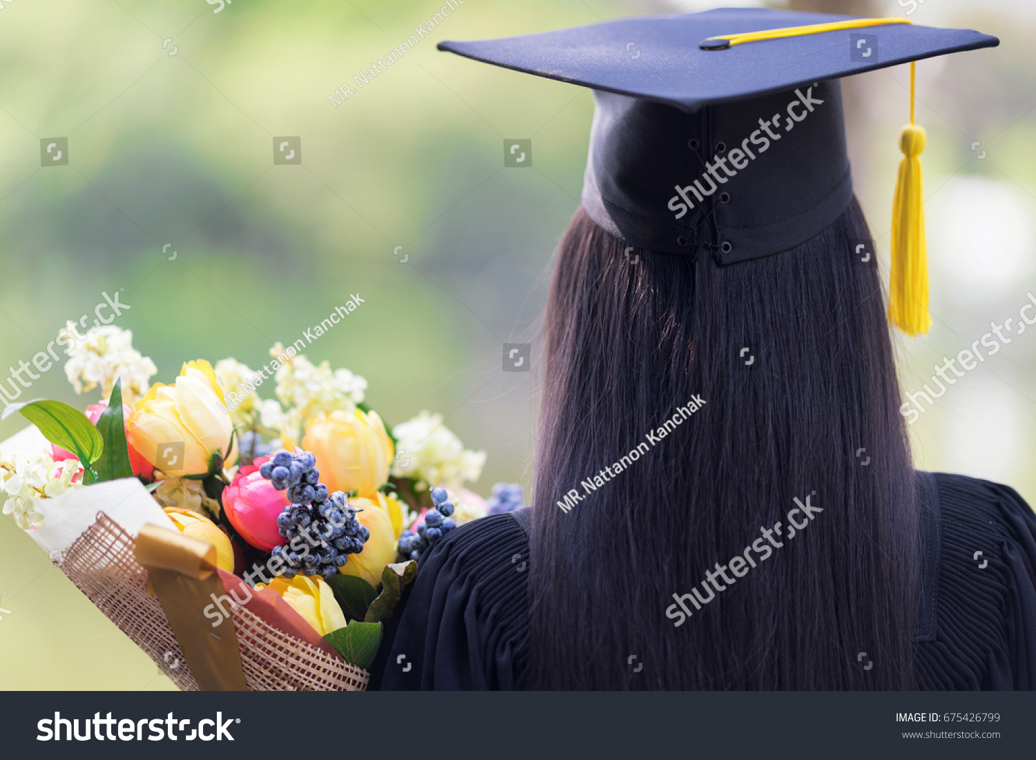Educational theme.Woman graduating and Beautiful bouquet of congratulations in an academic gown. #675426799