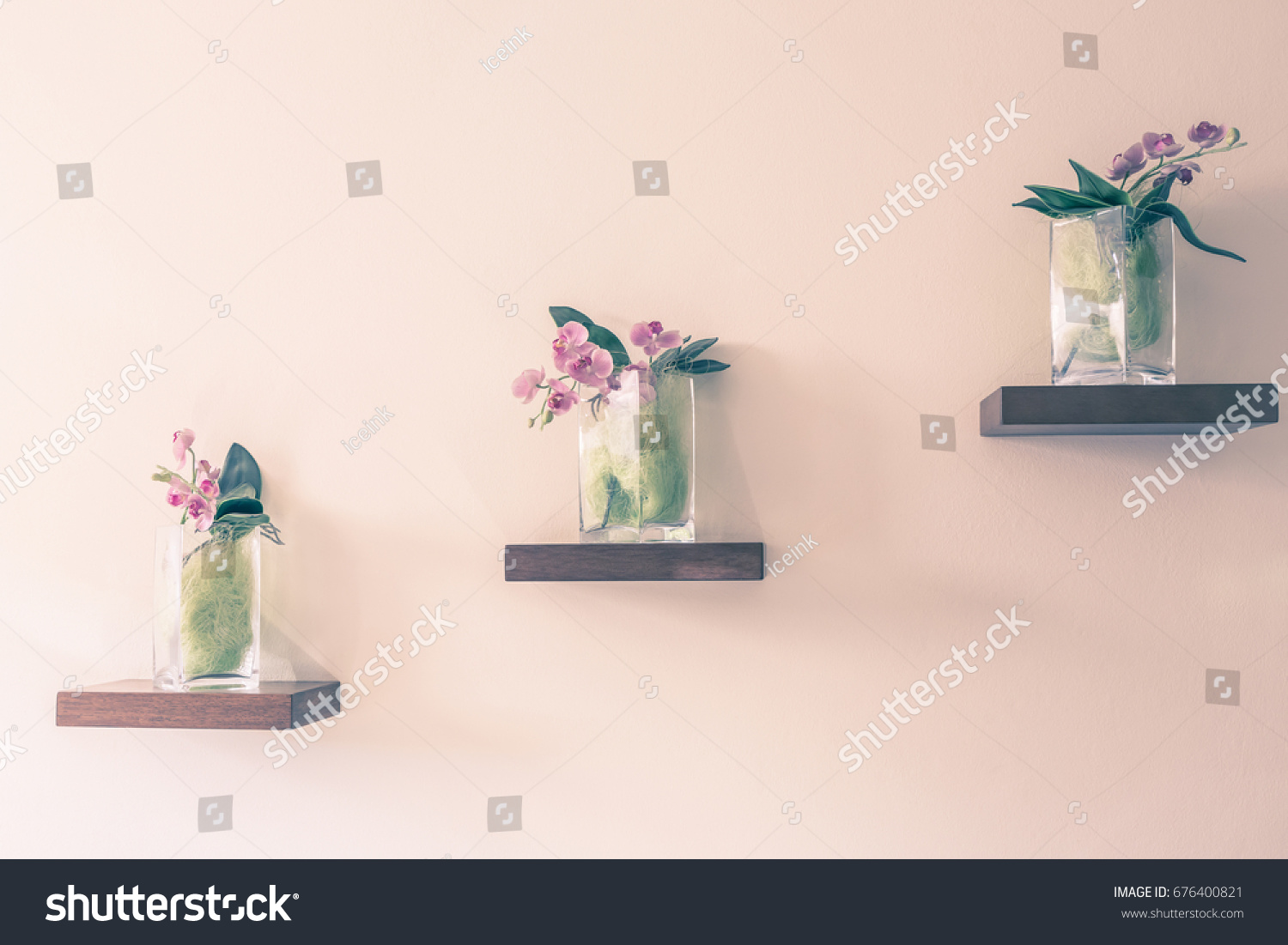 Beautiful orchid in glass vase on shelf on the wall background. Vintage color tone. #676400821