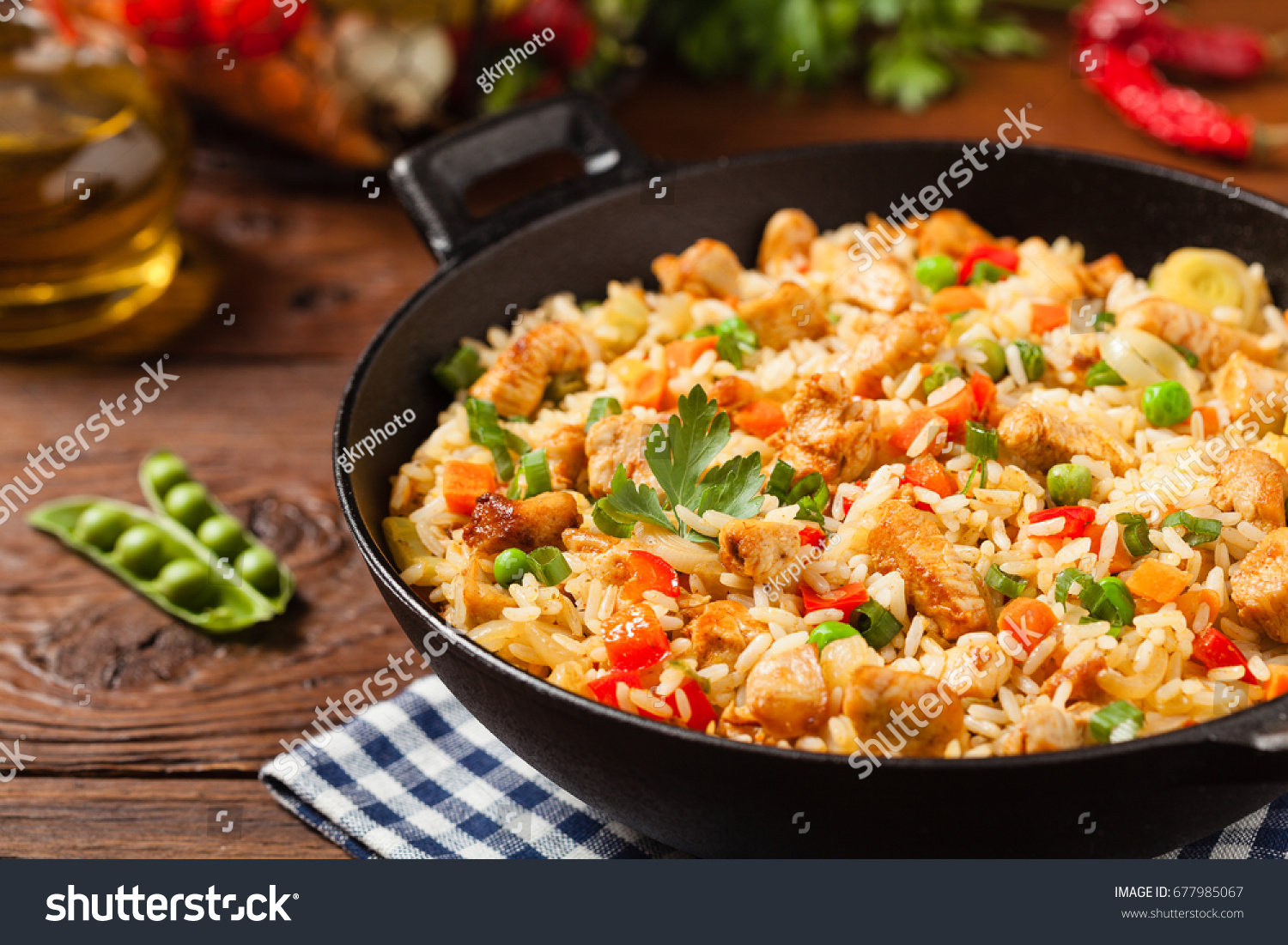 Fried rice with chicken. Prepared and served in a wok. Natural wood in the background. Front view. #677985067
