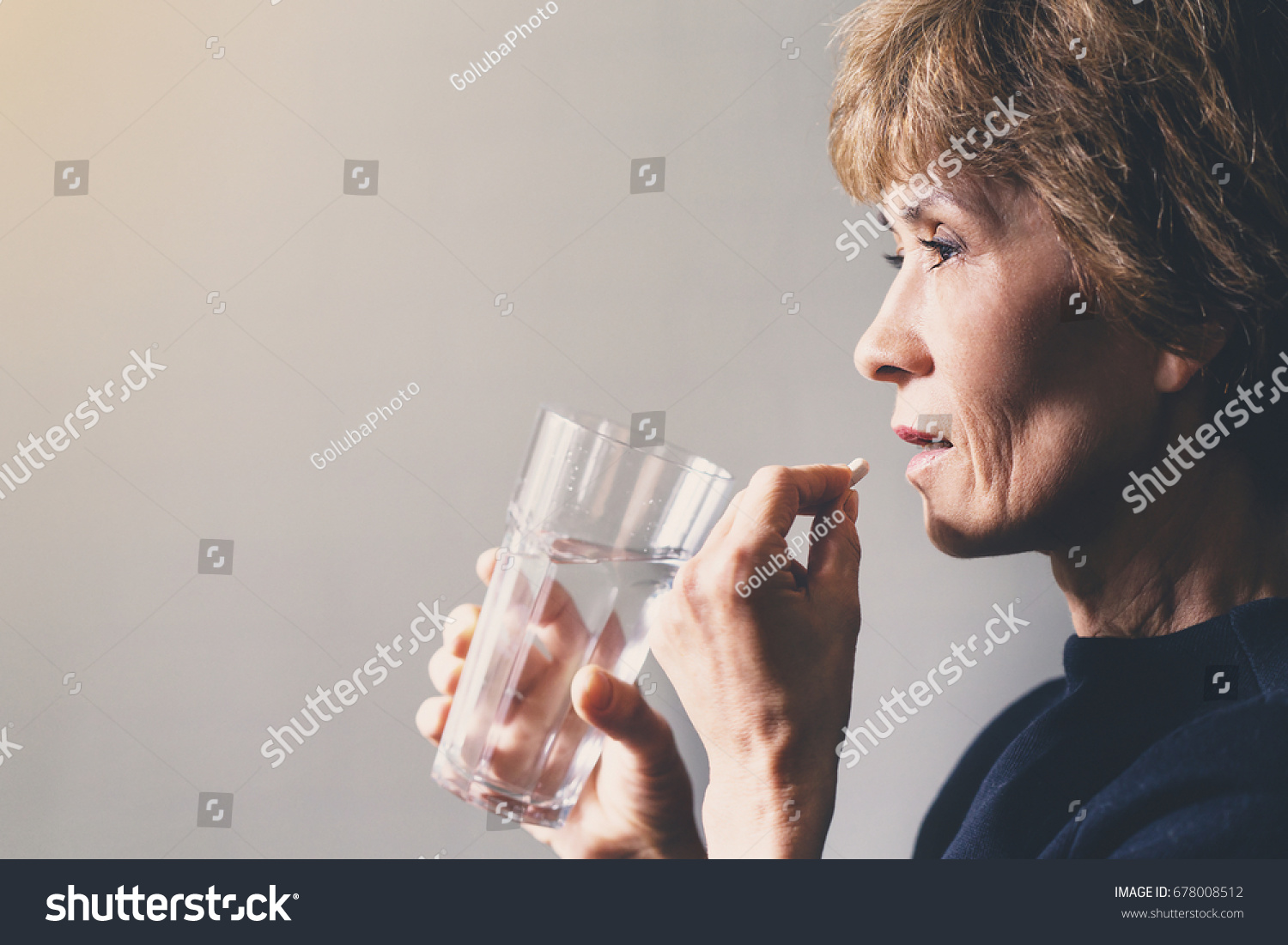 Adult woman with a pill and a glass of water / healthcare concept #678008512