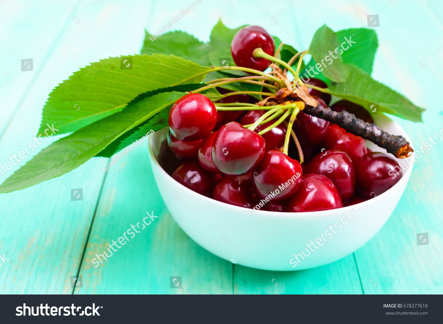 Ripe juicy red cherries in a ceramic bowl on a bright wooden background #678277618