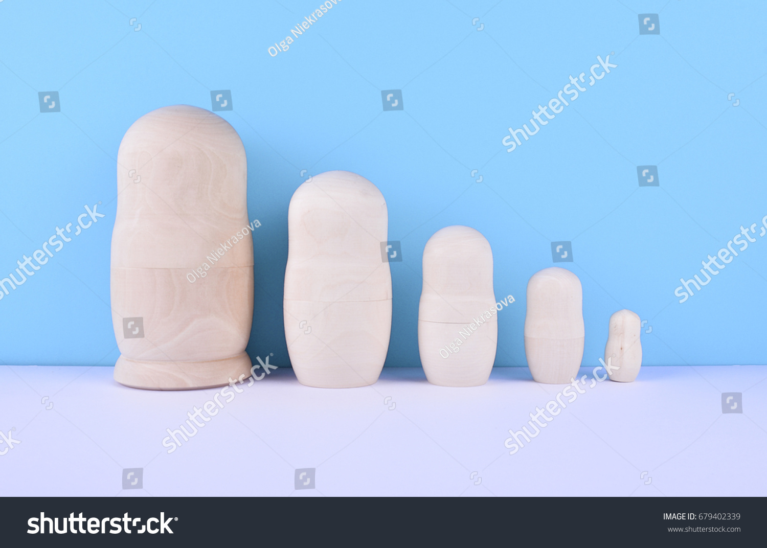 Wooden unpainted russian nested dolls (matryoshka) on blue background. Family concept. #679402339