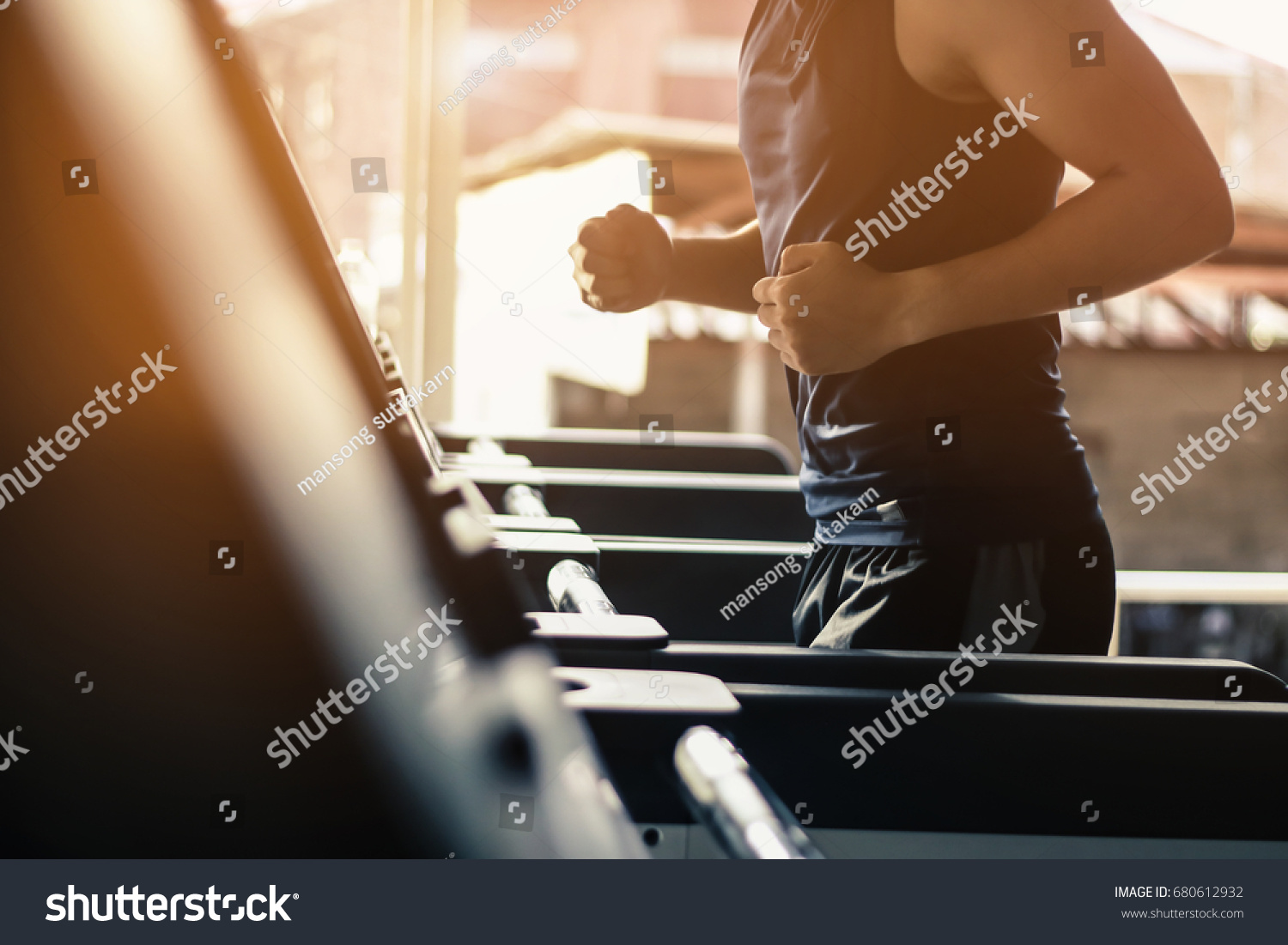 Man running in a modern gym on a treadmill concept for exercising, fitness and healthy lifestyl.lowkeylight.vintage tone.selective focus. #680612932