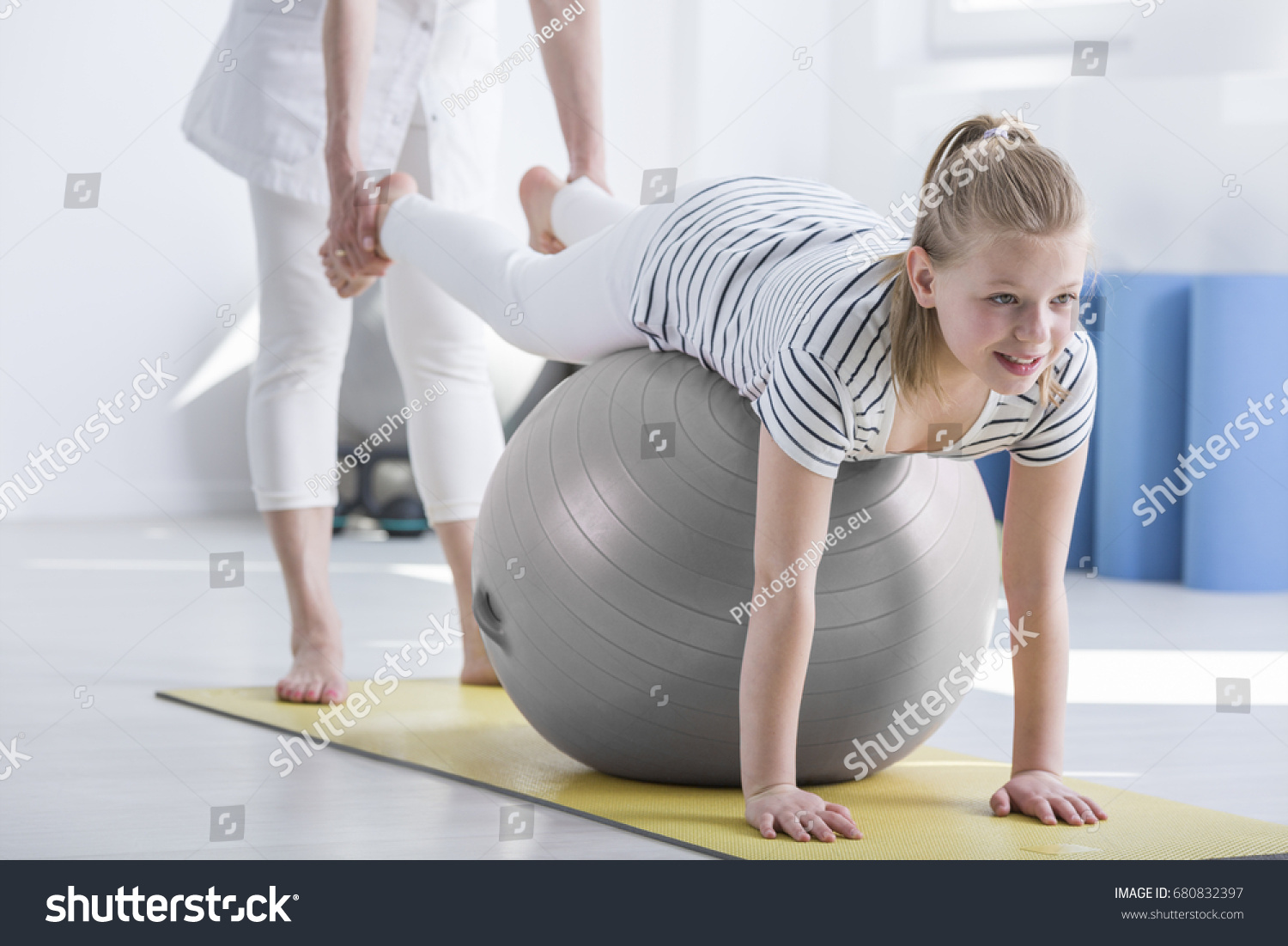 Smiling young girl lying on ball during pediatric occupational therapy #680832397
