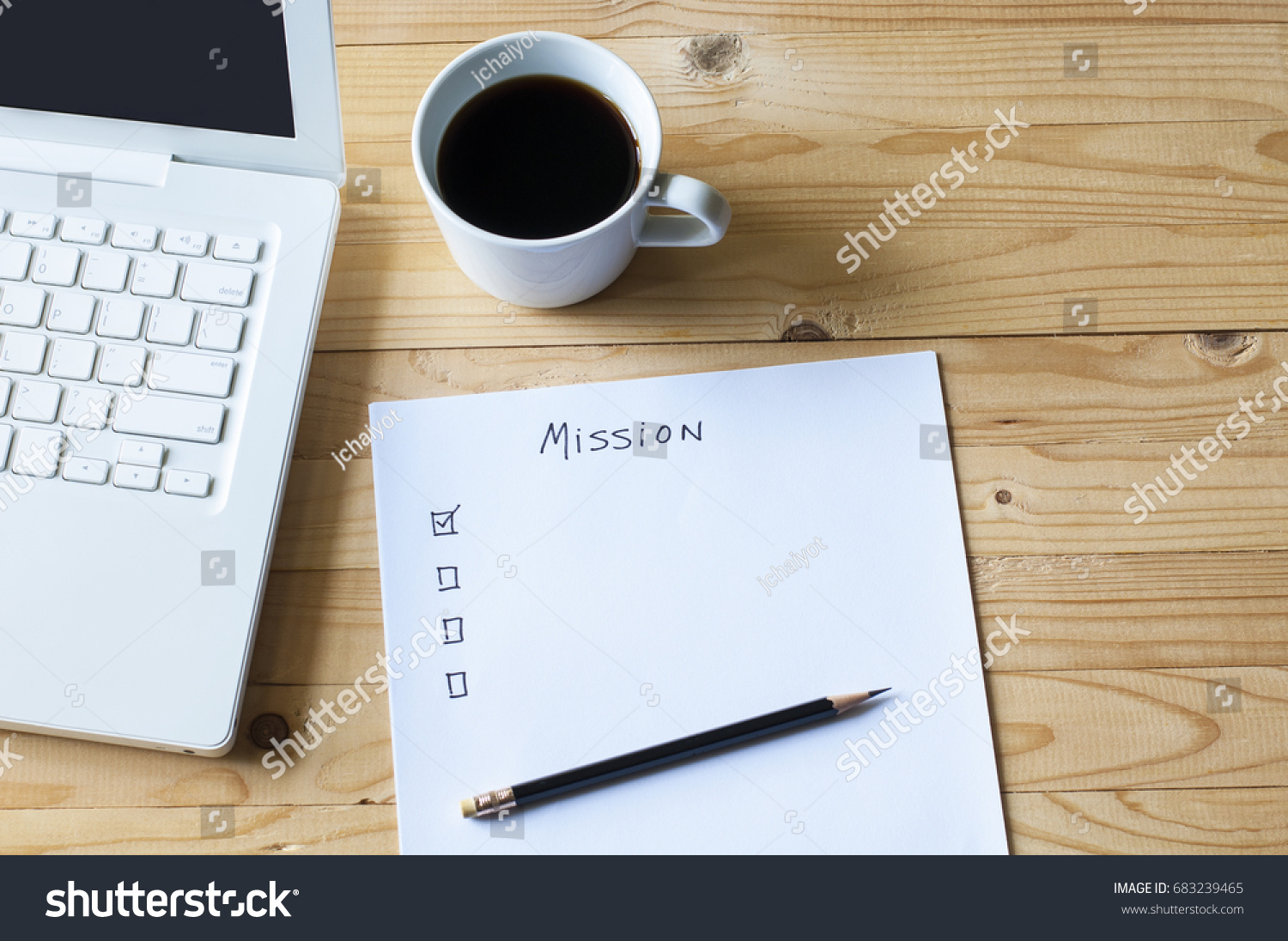 Paper check list for mission laptop and coffee on wood table. #683239465