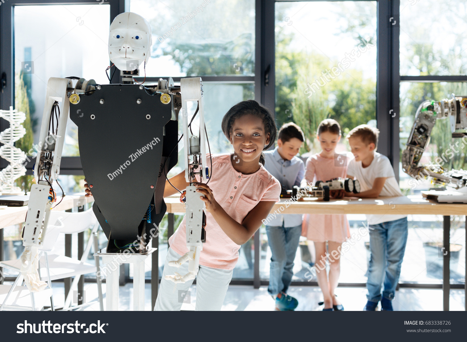 Pleasant girl looking out from behind a human robot #683338726
