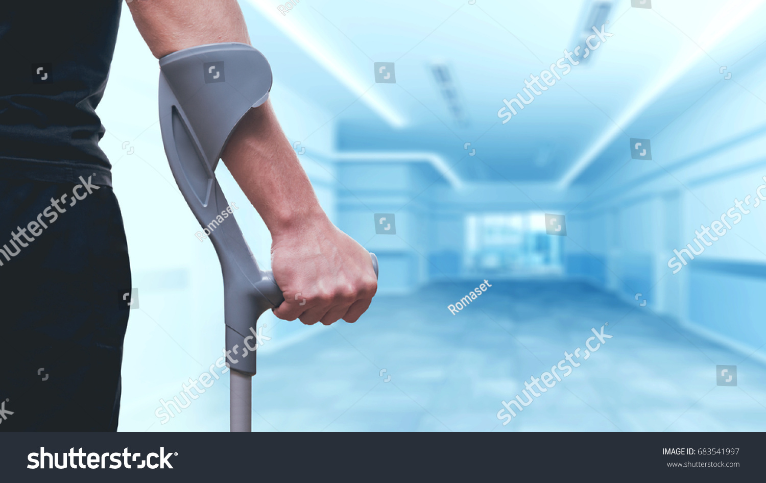 Injured man trying to walk on crutches. Blurred background #683541997