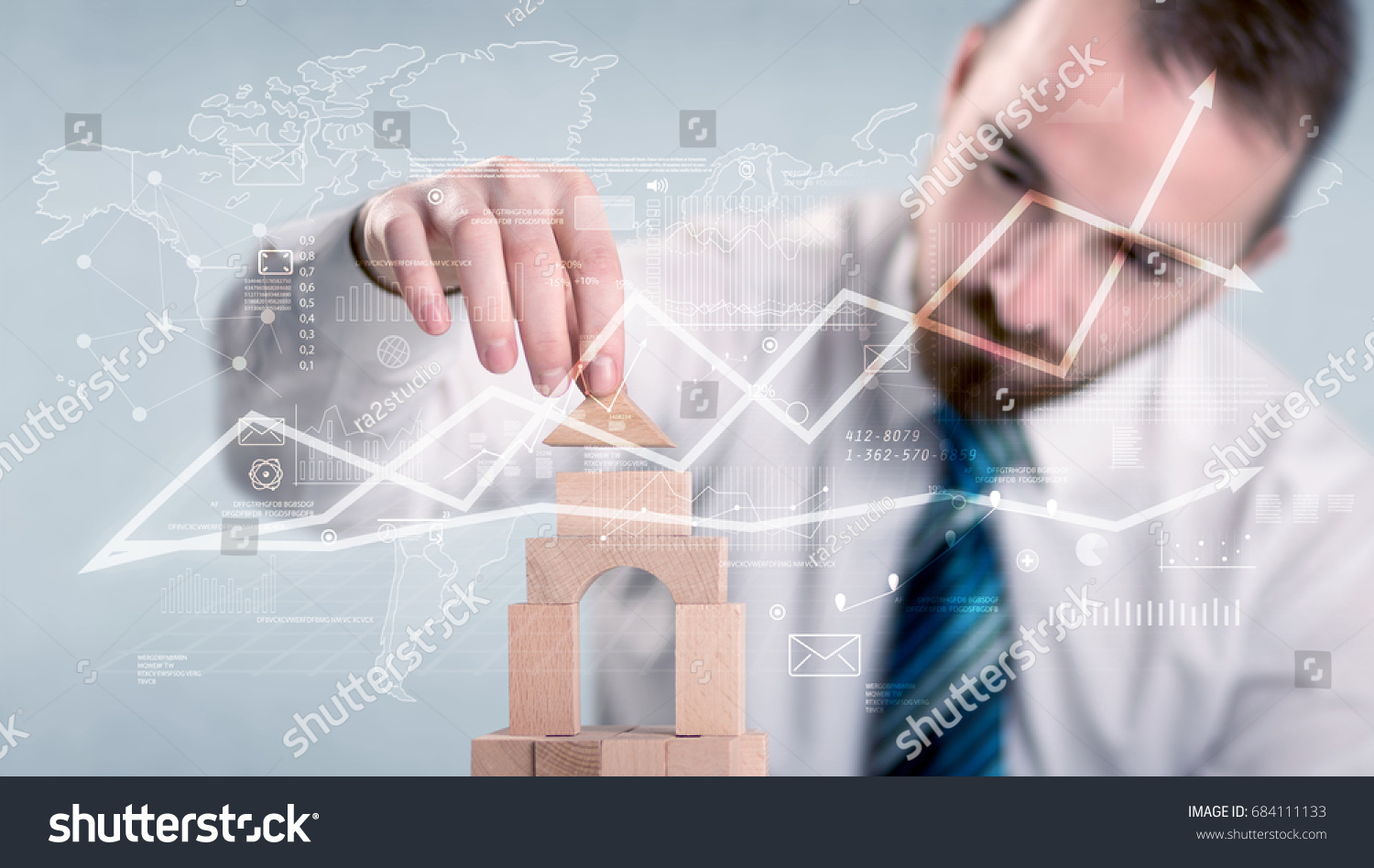 Young handsome businessman using wooden building blocks with data and calculations behind him #684111133