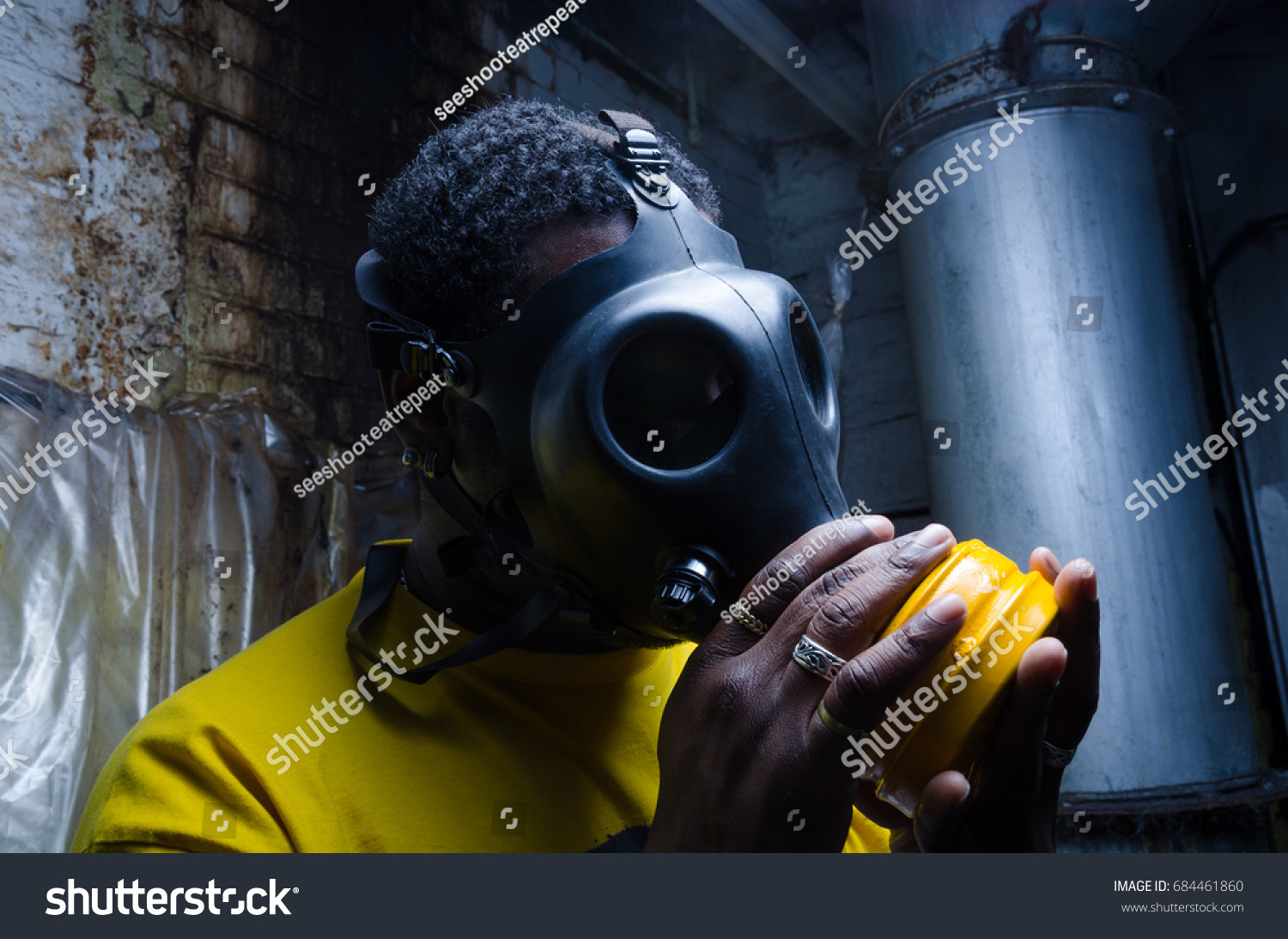 A scary man with reflection eyes in an industrial setting wearing a horror gas mask staring and intimidating. A horror movie character. #684461860