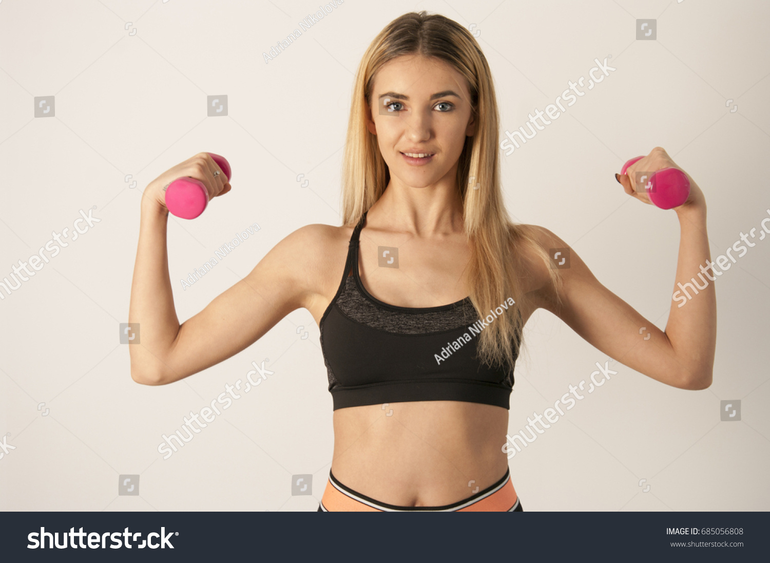 Young sport sexy fitness blonde woman posing on white wall in a tank top and leggings, sneakers #685056808