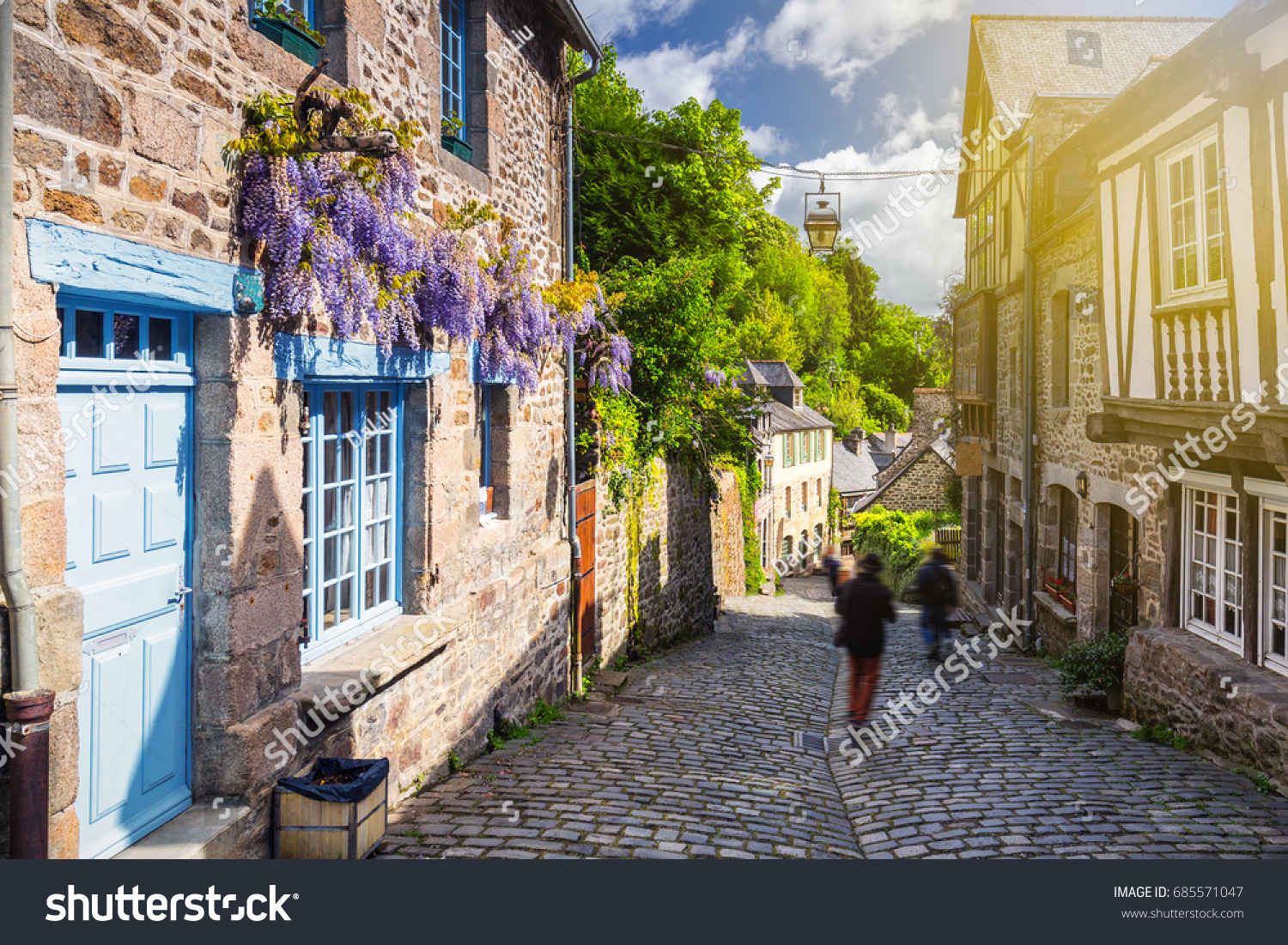Beautiful view of scenic narrow alley with historic traditional houses and cobbled street in an old town of Dinan with blue sky and clouds. Brittany (Bretagne), France #685571047
