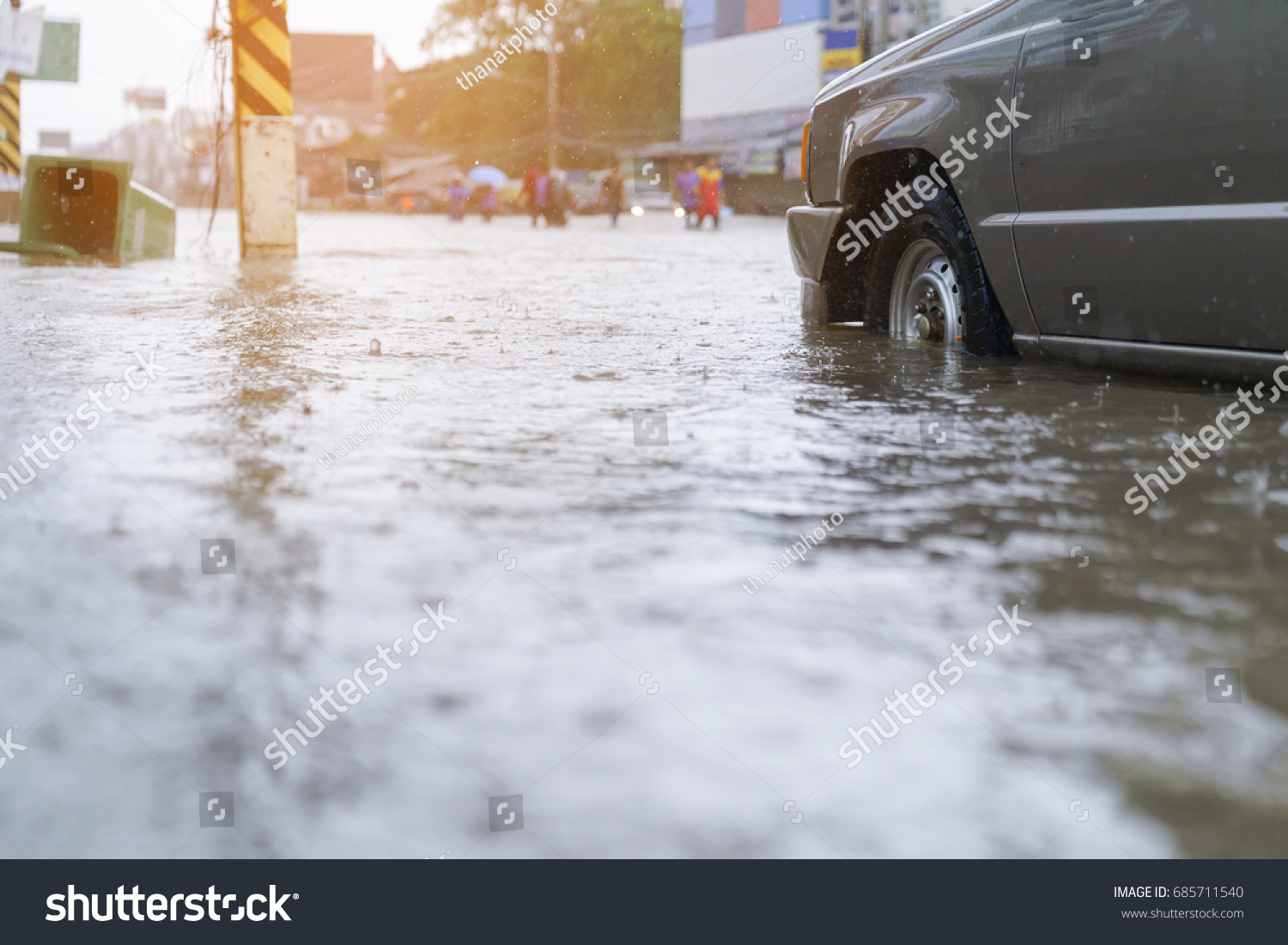 flood water - people walking in the rain on flooded road #685711540