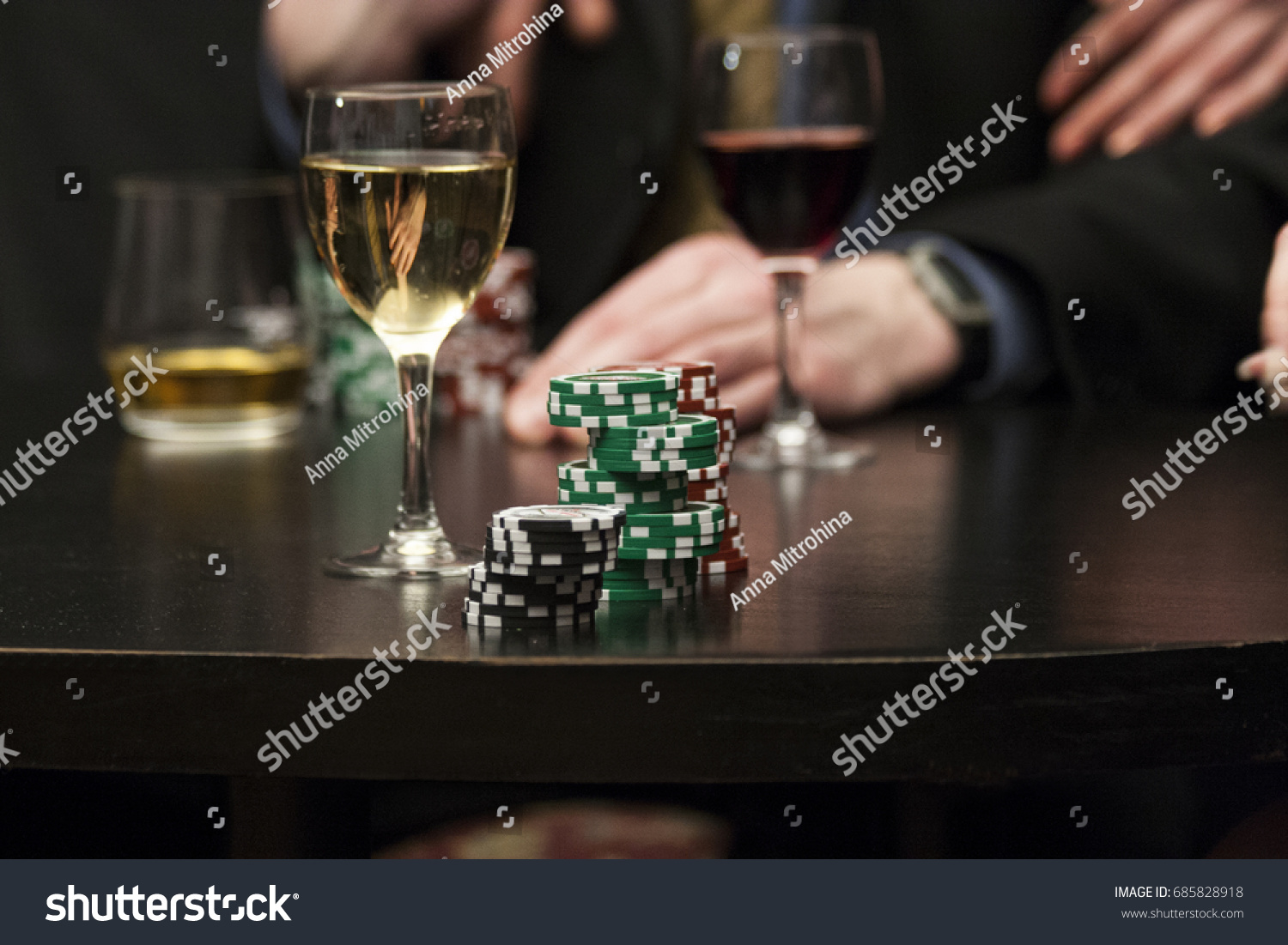 Poker chips on black table and red and white wine background #685828918