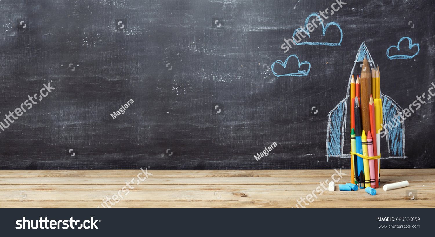 Back to school concept with rocket made from pencils over chalkboard background #686306059