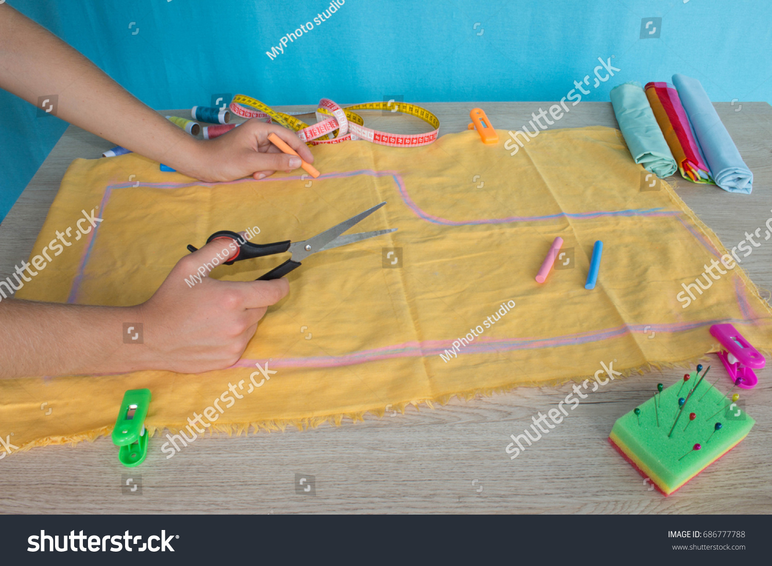 Tailor cutting fabric using large scissors or shears as he follows the chalk markings of the pattern, close up of his hands. Woman's Hand Sewing Quilt #686777788