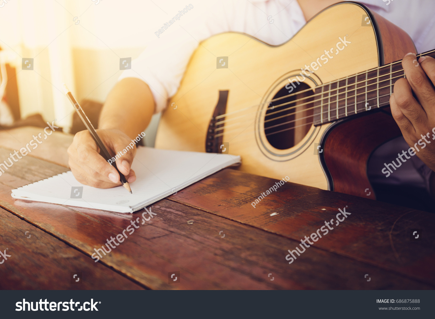 soft and blur focus.song writer holding pencil compose a song.musician playing acoustic guitar.empty space for text.concept for live music festival.Instrument on stage,abstract musical background. #686875888
