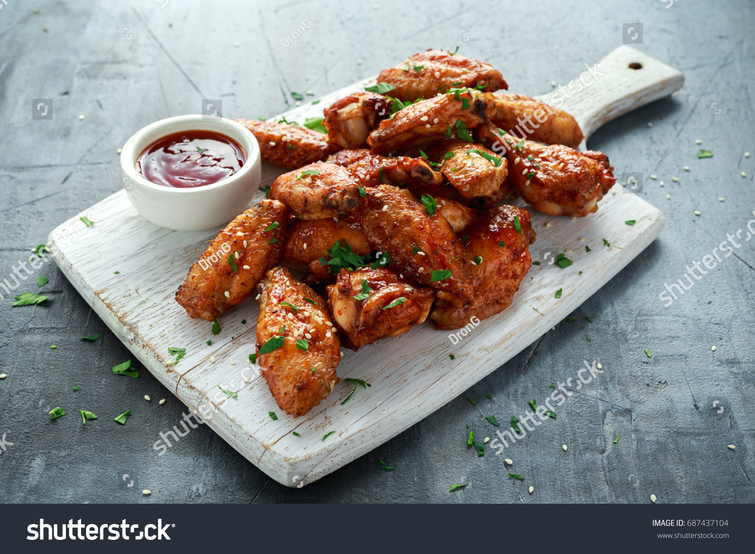 Baked chicken wings with sesame seeds and sweet chili sauce on white wooden board. #687437104