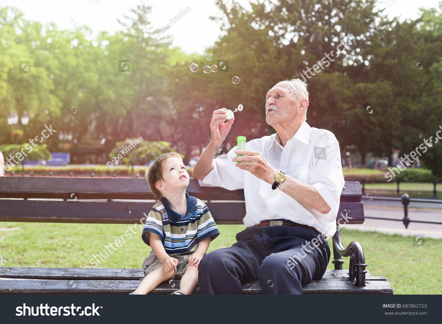 grandfather blowing soap bubbles to his grandchild #687862723