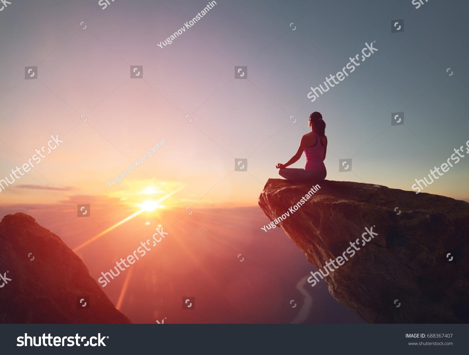 Woman practices yoga and meditates on the mountain. #688367407