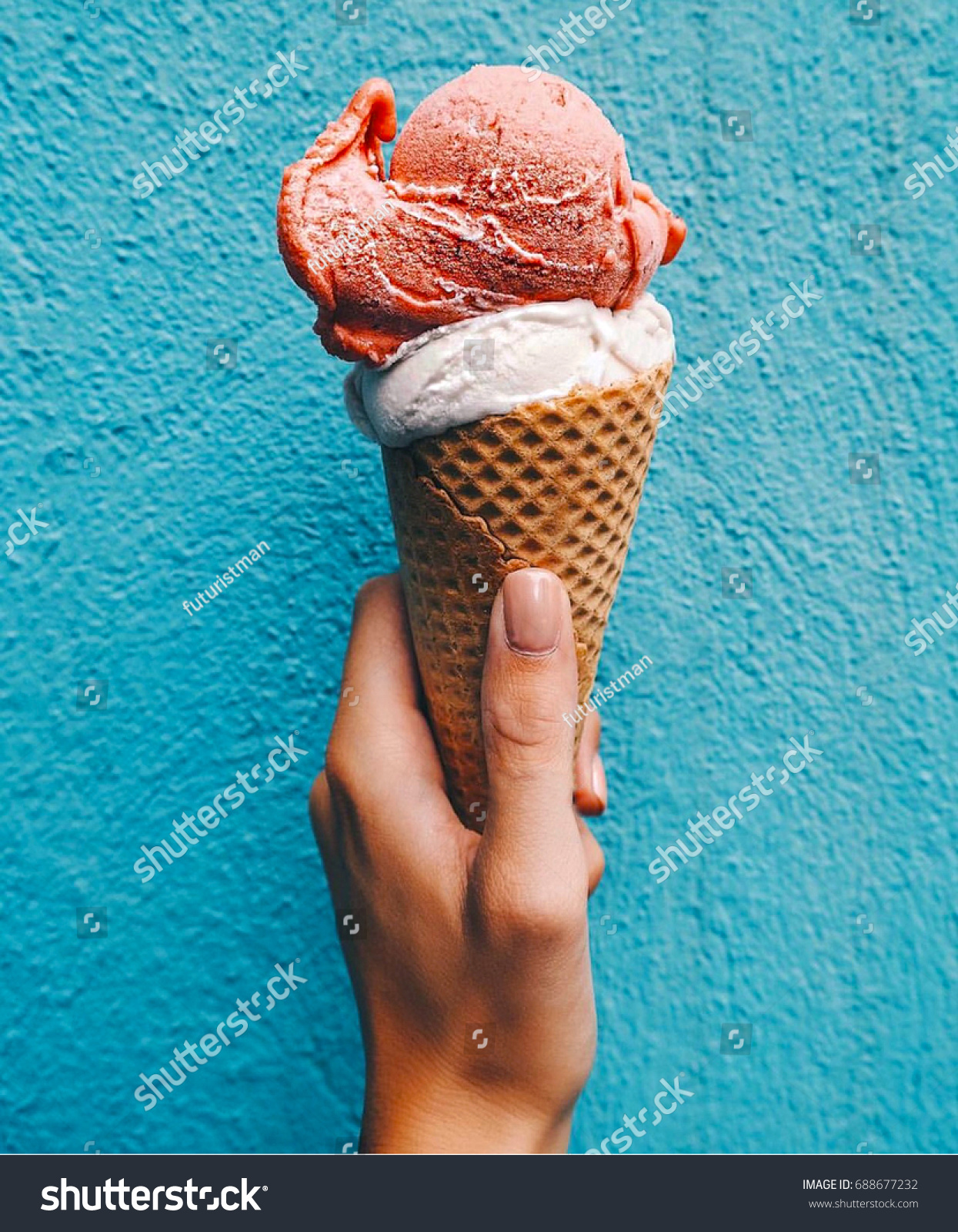 Ice cream cone on a blue background. The woman holding the ice cream by hand. #688677232