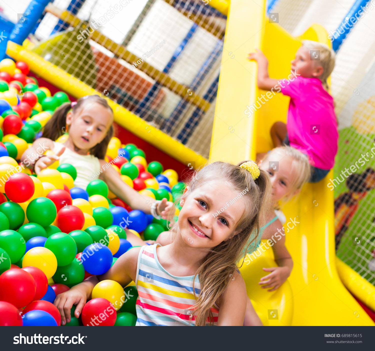 portrait of small smiling girl playing in pool with plastic multicolored balls
 #689815615