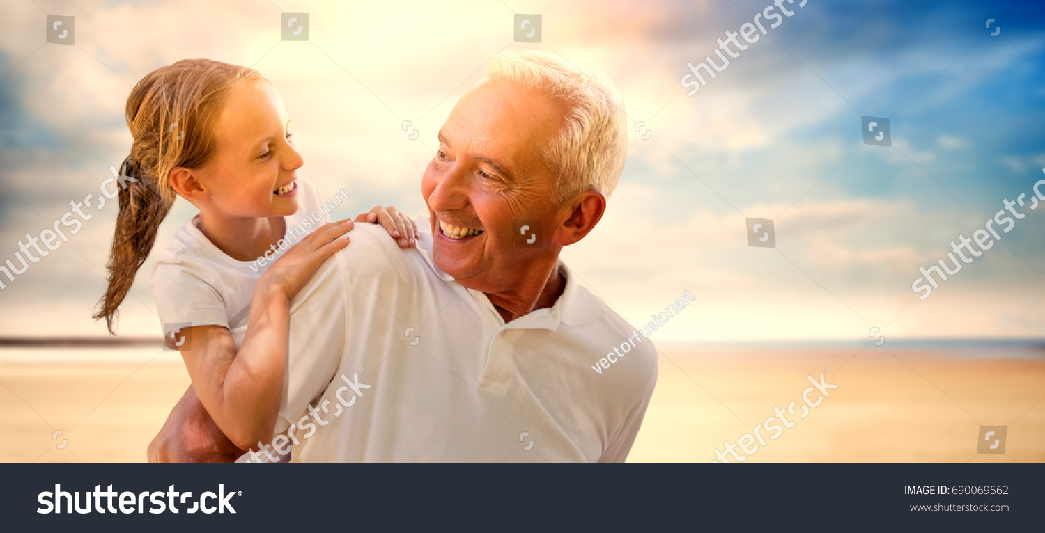 Grandfather holding his grandchild on his back against serene beach landscape #690069562