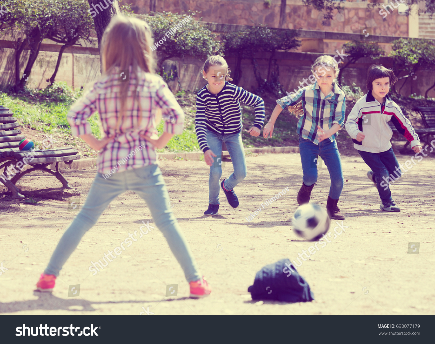 Portrait of active junior school girls and boy playing street football #690077179