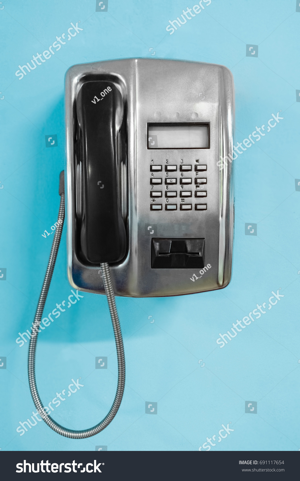 Metal Public Telephone on blue wall. Old payphone concept #691117654