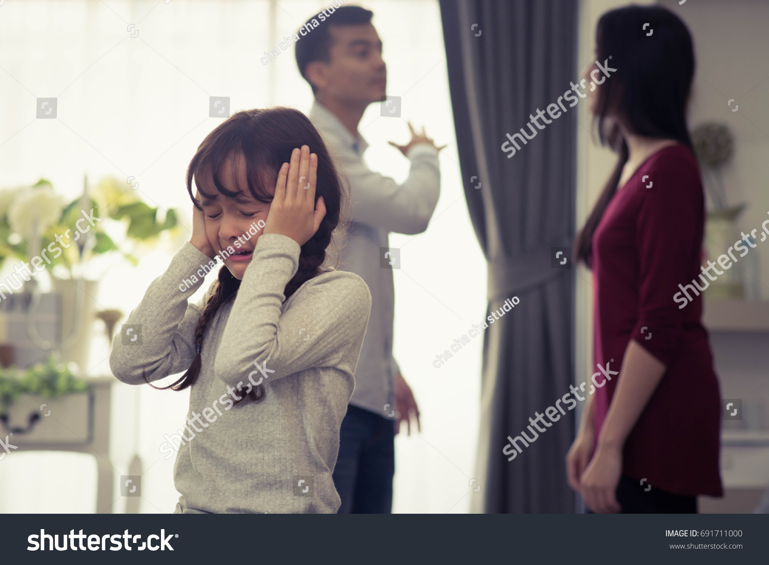 Little Girl Unhappy And Crying Fighting Parents Behind. Violence and Divorce  Family concept. #691711000