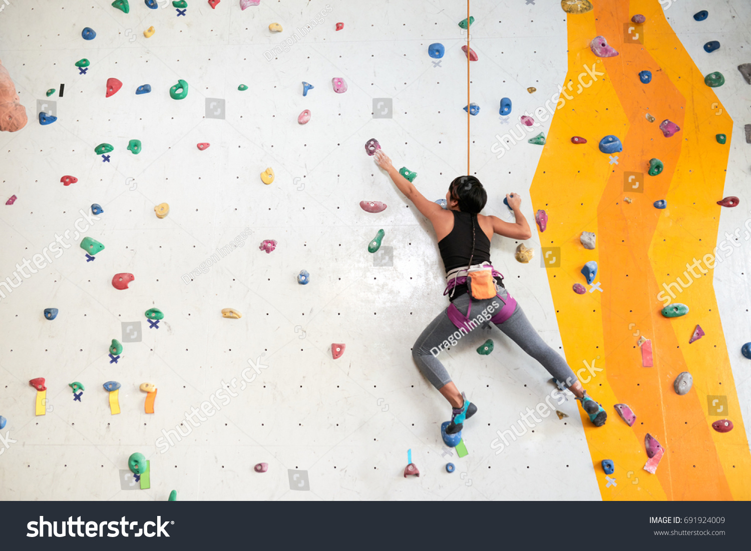 Woman climbing on the wall, view from the back #691924009