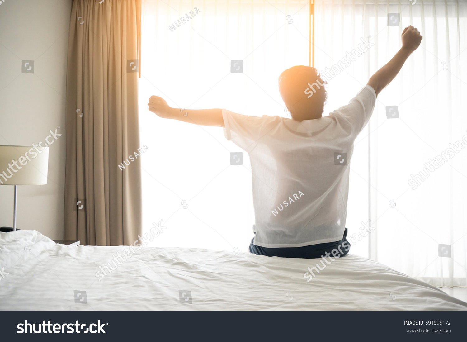 Man wake up and stretching in morning with sunlight #691995172