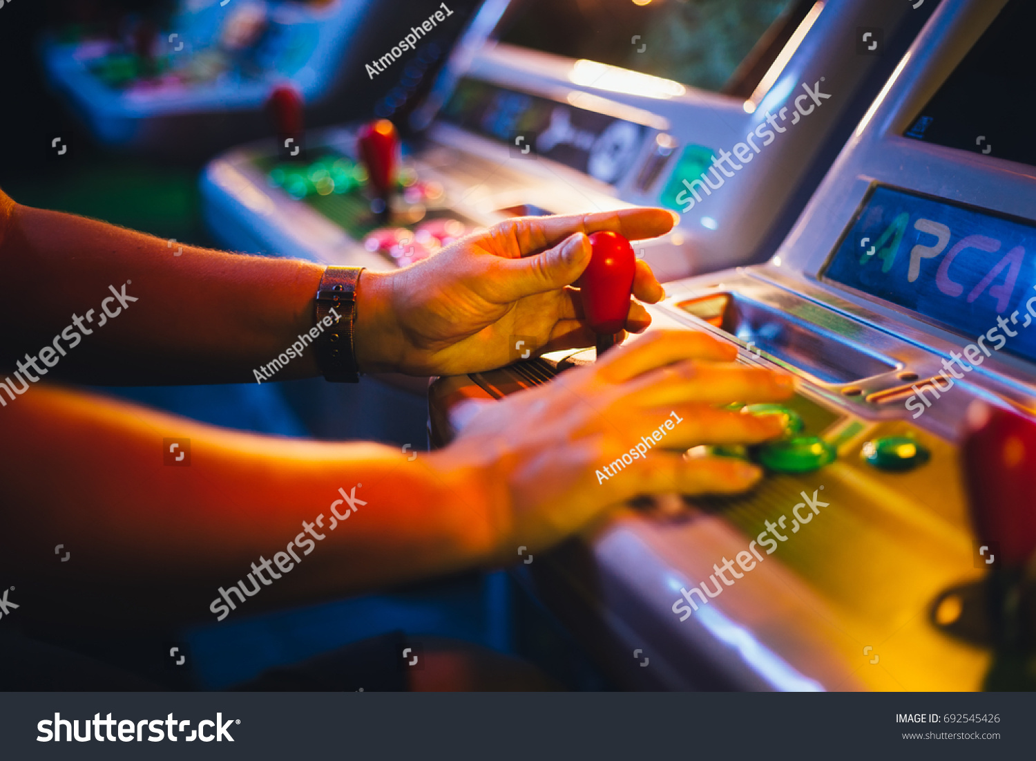 Detail on Hands with Arcade Joystick Playing Old Arcade Video Game #692545426