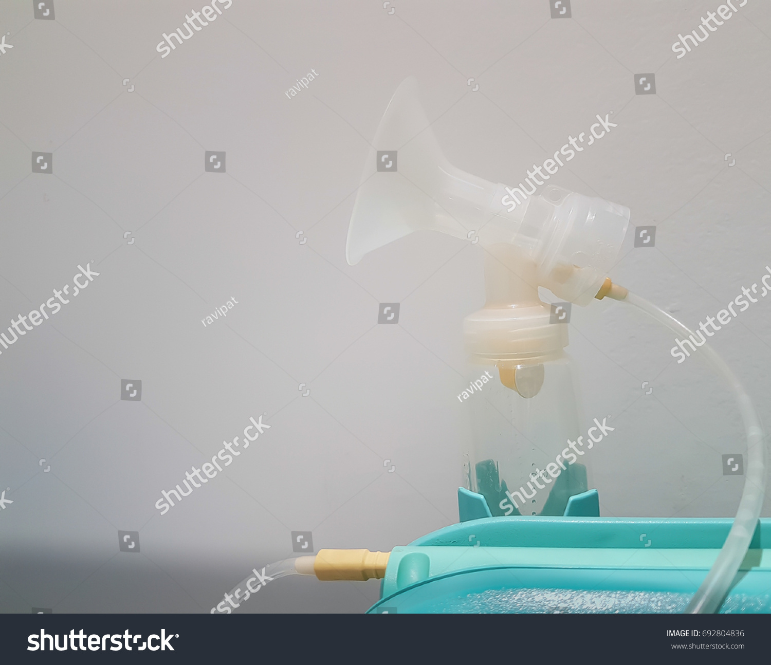 Breast pump with a bottle filled with breast milk .A breast pump is a mechanical device that extracts milk from the breasts of a lactating woman, Electric Breast Pump. #692804836