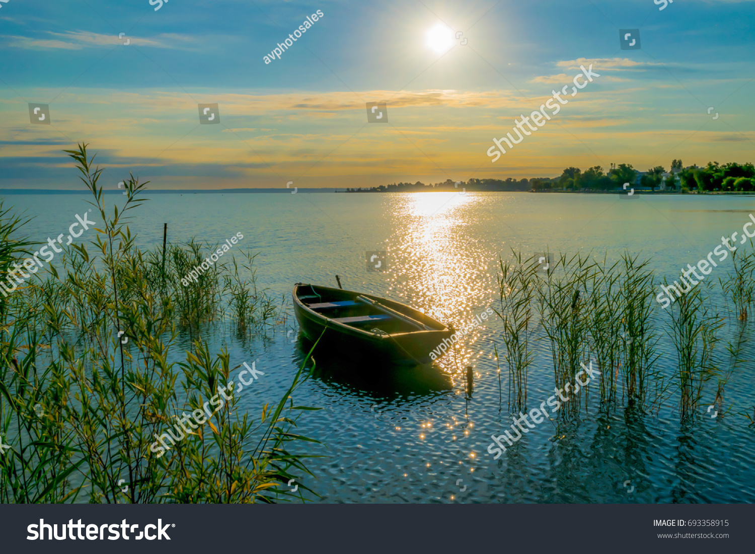 Rowing boat on lake at sunset
Small wooden rowing boat on a calm lake at sunset reed
 #693358915