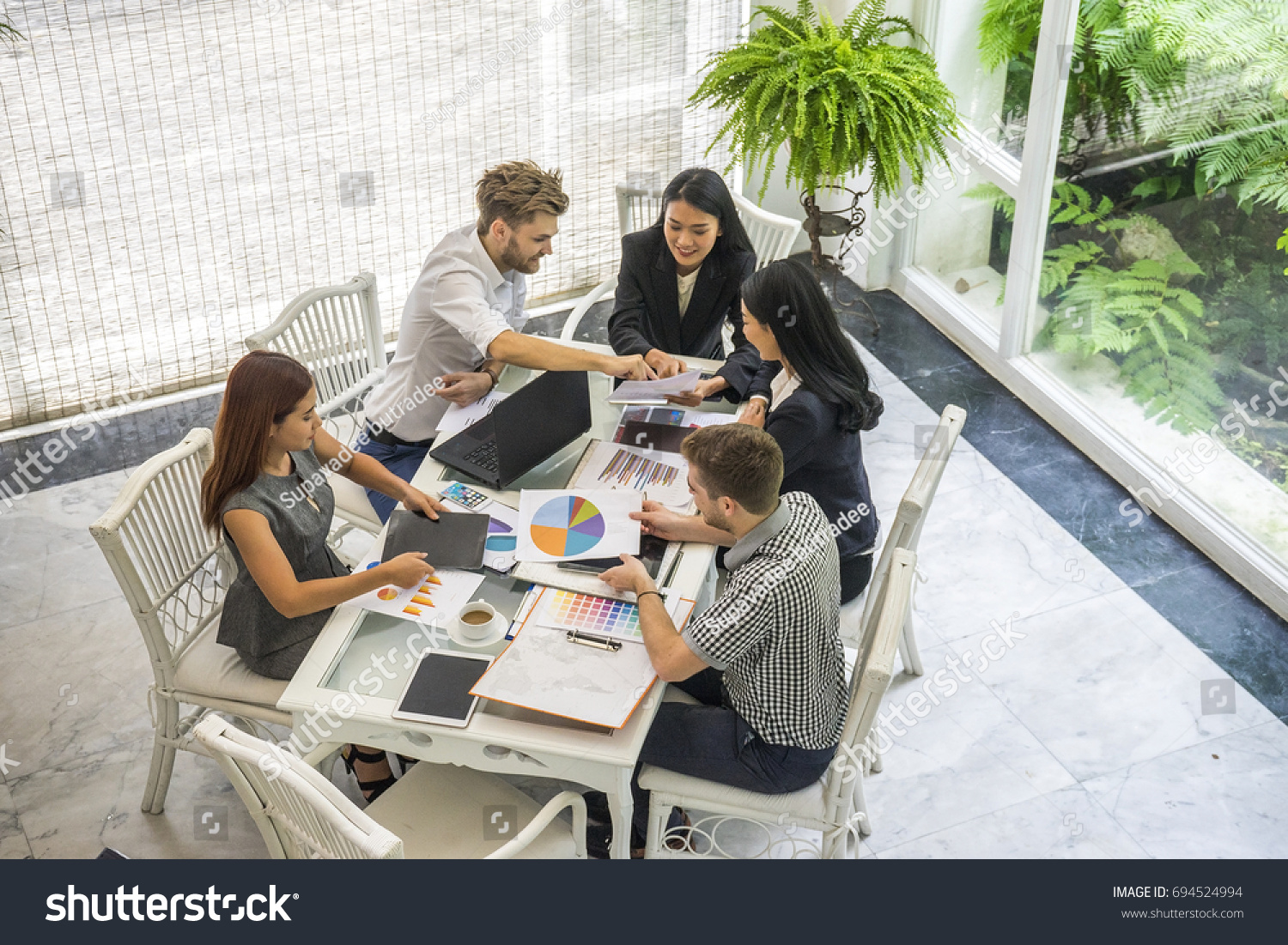 Group of casually dressed businesspeople discussing ideas in the office. Creative professionals gathered at the meeting table for discuss the important issues of the new  #694524994