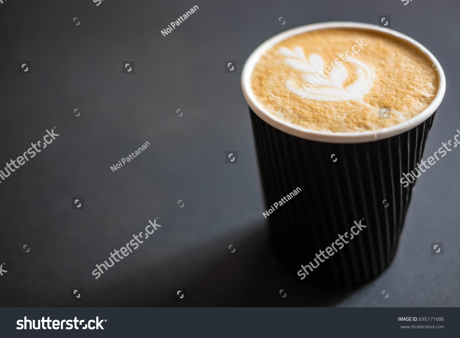 Soft focus of Latte art hot coffee in black paper cup on gray background with shadow , blurred and soft focus image #695171686
