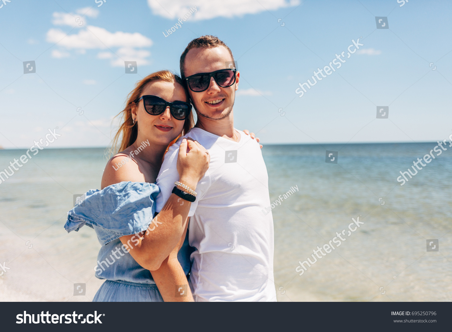 Young traveling couple walking along sandy beach near the sea #695250796