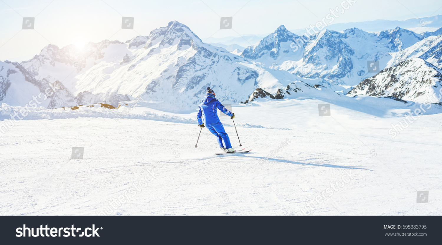 Young athlete skiing in Deux Alps french mountains on sunny day - Skier riding down for winter snow sport competition - Training and vacation concept - Focus on him - Warm filter  #695383795